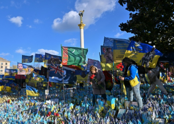 Women lay flowers in tribute to fallen Ukrainian soldiers at a makeshift memorial in Kyiv. ©AFP