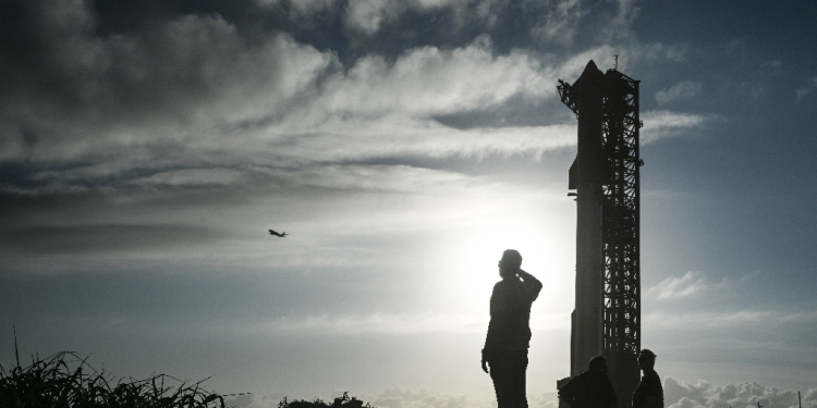 A man watches a SpaceX plane as it flies past the SpaceX Starship at the launch pad ahead of its sixth flight test from Starbase in Boca Chica, Texas / ©AFP