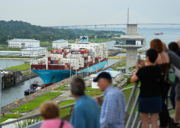 Tourists watch a Danish-flagged cargo ship passing through the Panama Canal / ©AFP