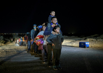 In a photo taken on March 27, 2021 a family of immigrants, who arrived illegally across the Rio Grande river from Mexico, stand in line at a processing checkpoint before being detained at a holding facility by border patrol agents in the border city of Roma.. ©AFP