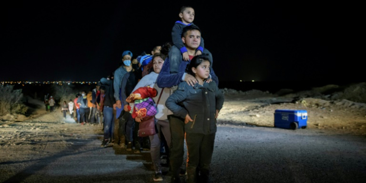 In a photo taken on March 27, 2021 a family of immigrants, who arrived illegally across the Rio Grande river from Mexico, stand in line at a processing checkpoint before being detained at a holding facility by border patrol agents in the border city of Roma.. ©AFP