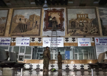 Anti-regime fighters tear off a poster depicting Syrian President Bachar al-Assad and his brother Maher at the airport in the northern Syrian city of Aleppo / ©AFP