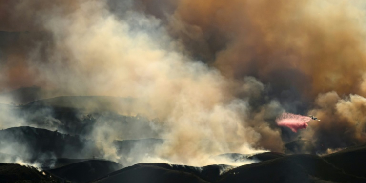 In this aerial view taken from a helicopter, an air tanker drops fire retardant on the Kenneth Fire in the Calabasas area of Los Angeles. ©AFP