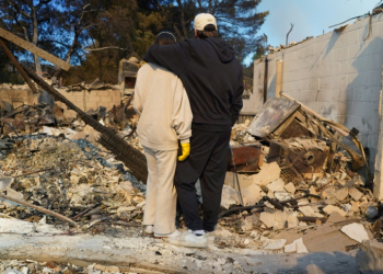 Kyle Kucharski hugs his partner Nicole Perri as they stand on the ruins of their house in the Pacific Palisades neighborhood of Los Angeles. ©AFP