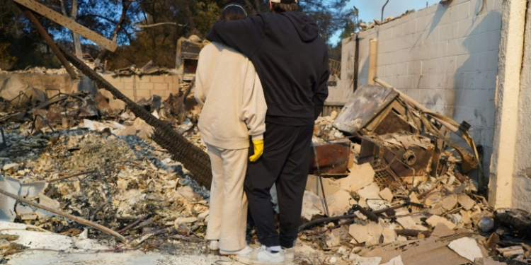 Kyle Kucharski hugs his partner Nicole Perri as they stand on the ruins of their house in the Pacific Palisades neighborhood of Los Angeles. ©AFP