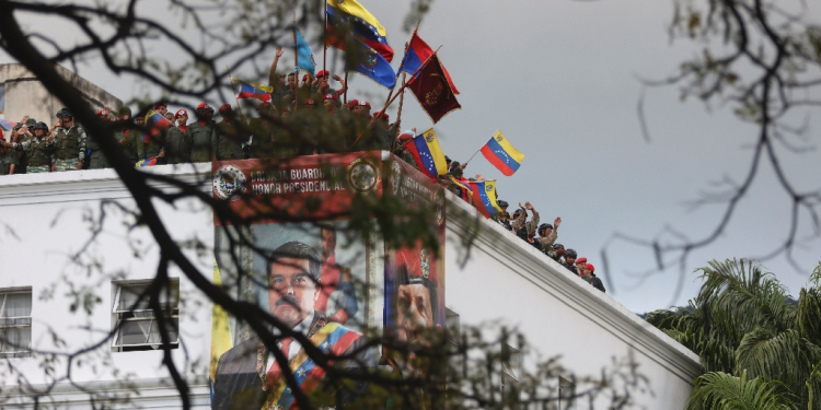 Members of the guard of honor of Venezuelan President Nicolas Maduro wave flags on the roof of the Miraflores presidential palace on January 23, 2025 / ©AFP