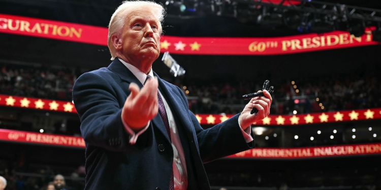 US President Donald Trump throws pens to the crowd after signing executive orders during his inaugural parade / ©AFP