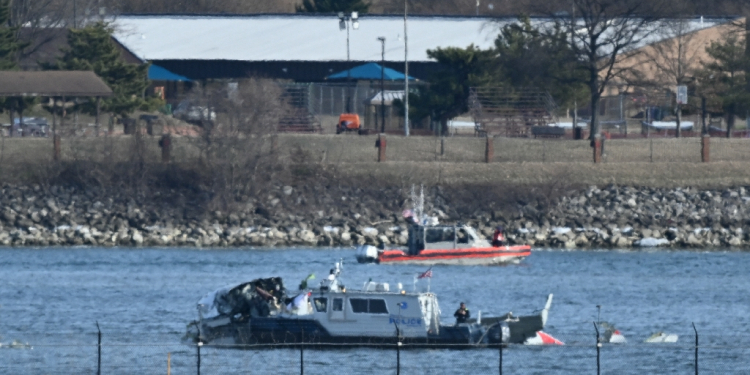 A police boat gathers wreckage along the Potomac River after American Airlines flight 5342 on approach to Reagan National Airport crashed into the river after colliding with a US Army helicopter / ©AFP