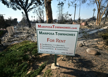 The remains of townhomes destroyed by the Eaton Fire lie behind an advertising sign in Altadena, California. ©AFP