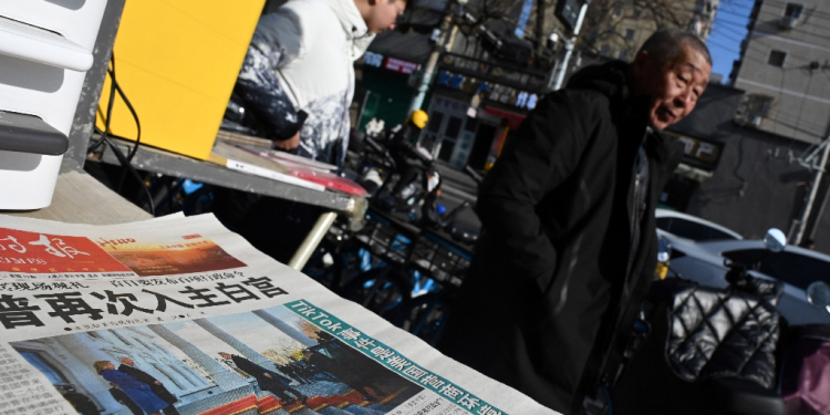 A newspaper featuring an image of Donald Trump arriving at the White House ahead of his inauguration as US President is seen at a news stand in Beijing on January 21 / ©AFP