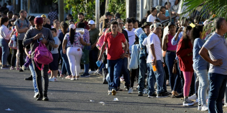 Migrants seeking permits allowing them to travel to the US border wait outside an immigration office in southern Mexico . ©AFP