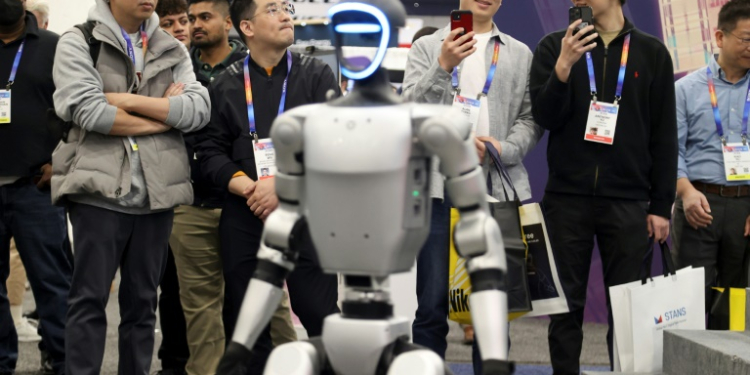 Attendees watch as a robot walks around during a demonstration at the Unitree Robotics booth during the Consumer Electronics Show (CES) in Las Vegas. ©AFP