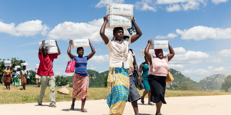 Mothers carry boxes of porridge backed by US aid in the Mutokoarea of Zimbabwe in 2019 as drought worsened hunger  / ©AFP